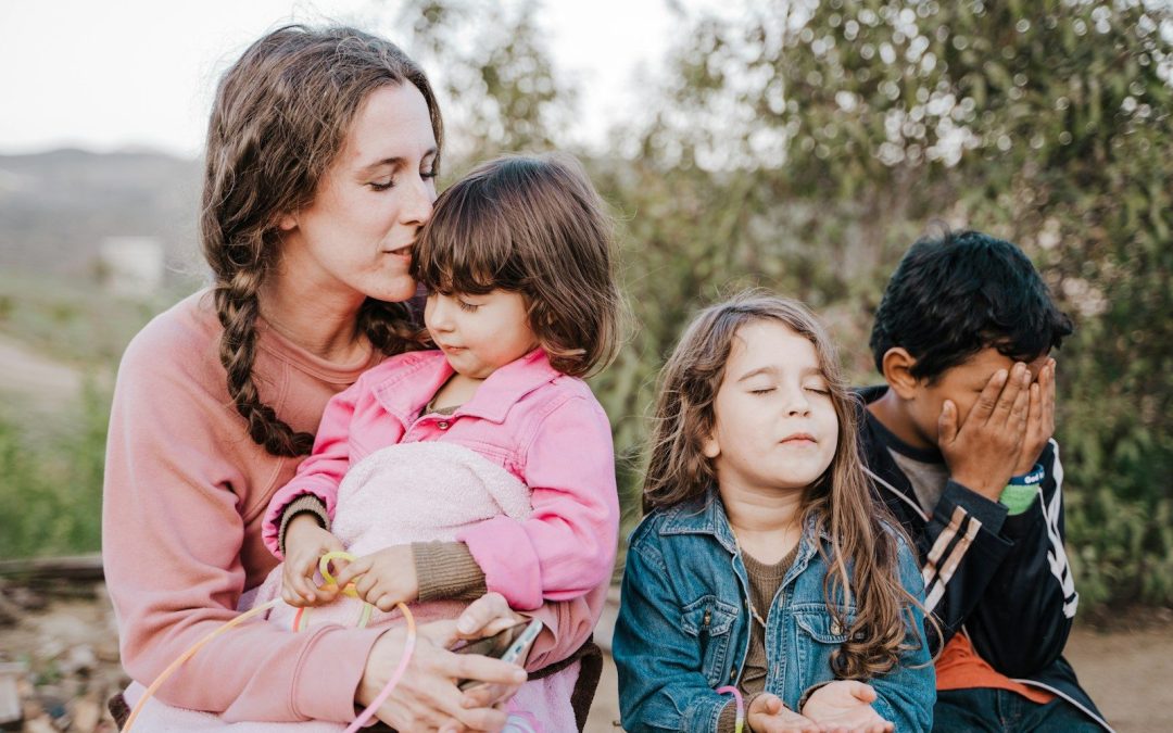 woman in blue denim jacket carrying girl in pink jacket during daytime